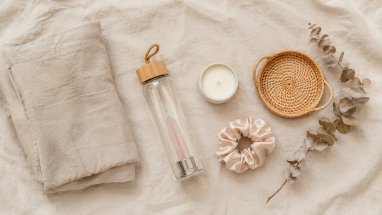 flatlay of amazon aesthetic finds including linen, candle, rattan tray and glass bottle