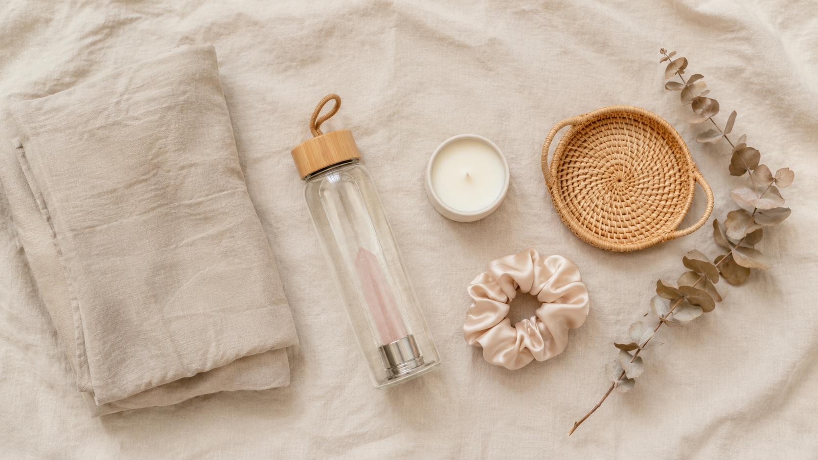 flatlay of amazon aesthetic finds including linen, candle, rattan tray and glass bottle