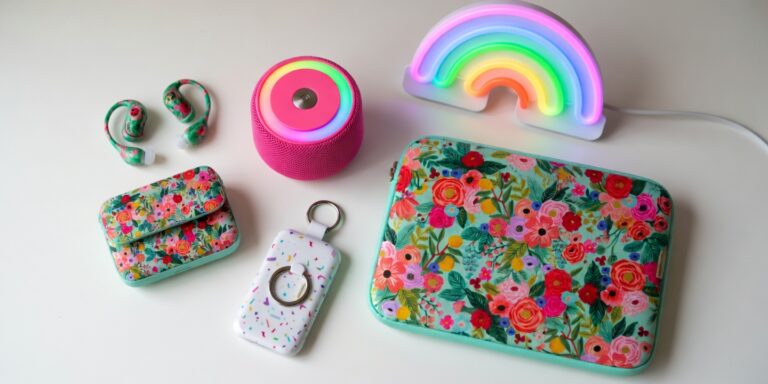 flatlay of y2k tech aesthetic finds including floral earbuds, neon rainbow lamp, confetti power bank and pink bluetooth speaker